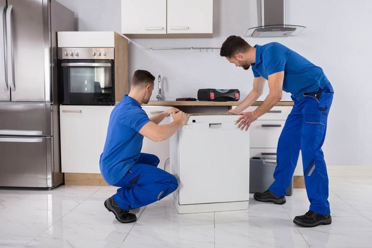 two movers placing dishwasher in kitchen